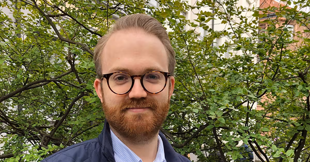 Mann med briller og skjegg foran et tre