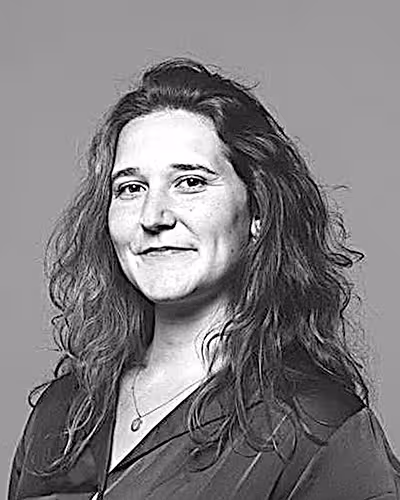 Kvinne med langt mørkt hår mot grå bakgrunn