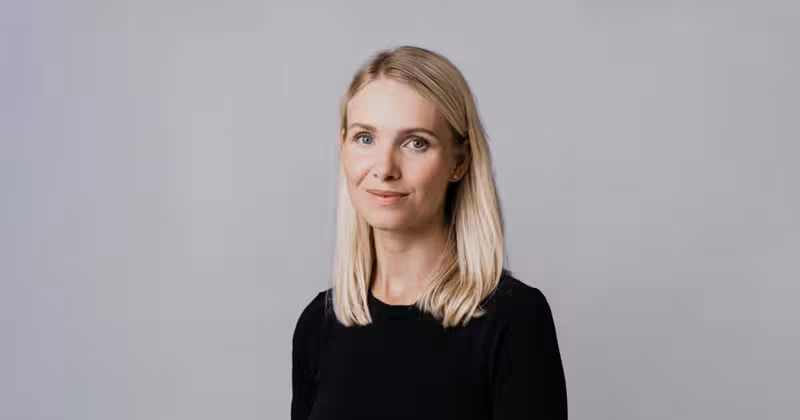 Blond, smilende kvinne mot hvit bakgrunn