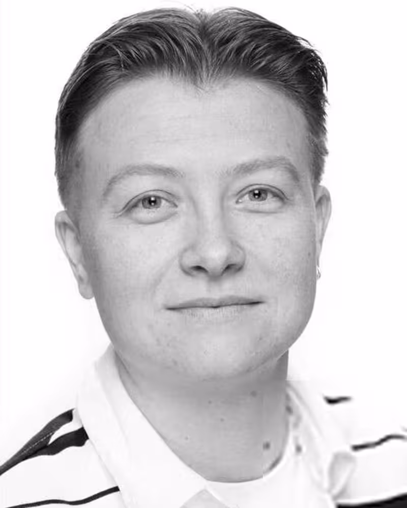 Svart-hvitt bilde av en smilende ung mann med midtskill